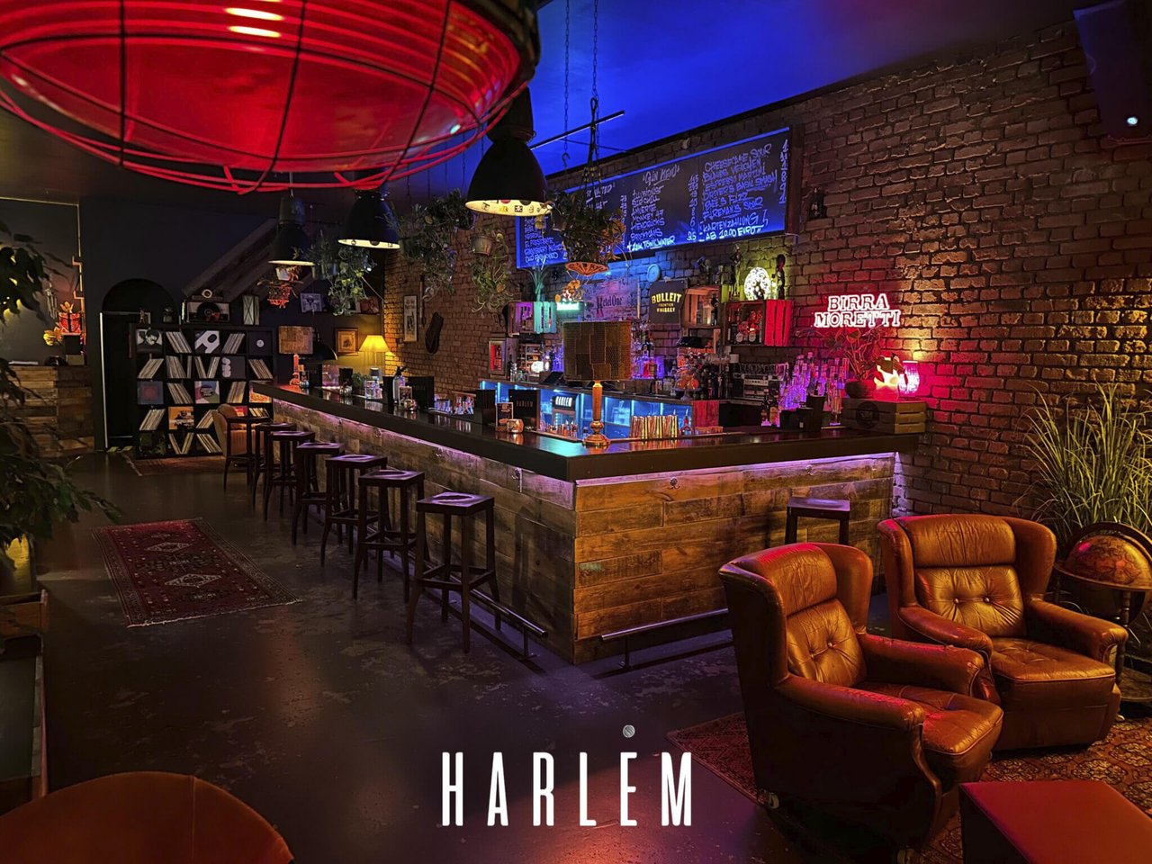 Innenansicht der Harlem Bar in Nürnberg – eine stilvolle Lounge im Industrial-Vintage-Design mit Holztheke, Backsteinwänden und Ledersesseln. Die moderne Bar gehört zur JIAOGULAN Holding AG und steht für urbane Gastkultur, Designästhetik und zukunftsorientierte Lifestyle-Investments.